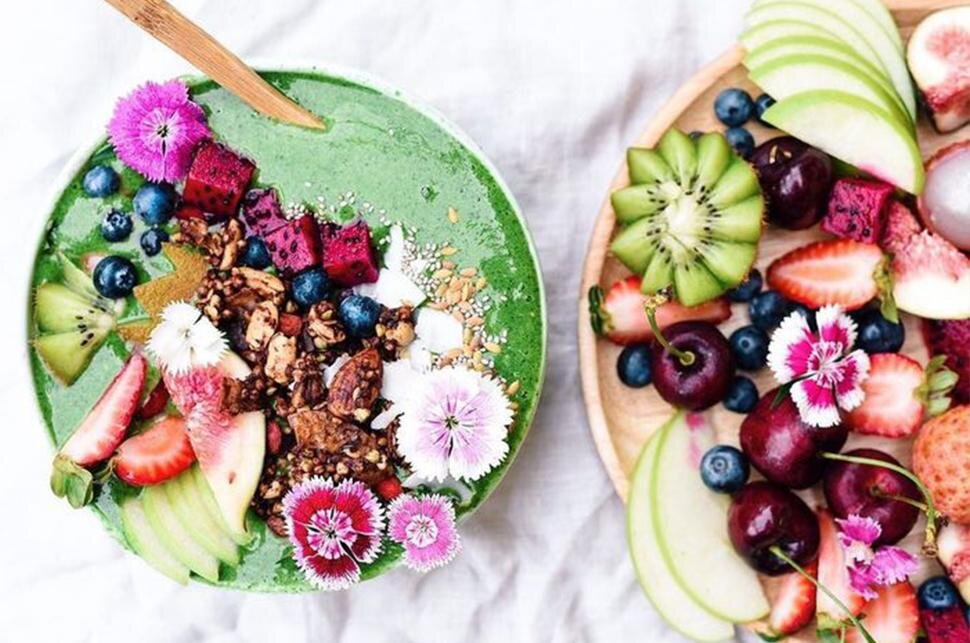 Colorful bowls of fruit, greens, and whole-food ingredients